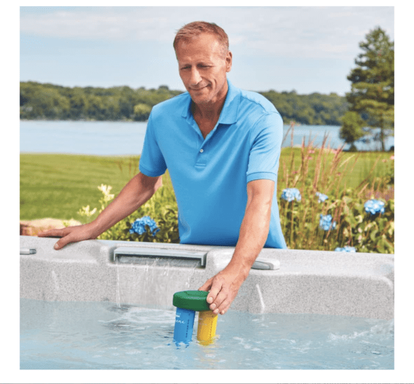 A man in a blue shirt cleaning a FROG Serene Floating Sanitizing System for Hot Tubs, Quick and Easy Self-Regulating Hot Tub Sanitizer with Bromine and FROG Sanitizing Minerals Kills Bacteria 2 Ways, for Hot Tubs up to 600 gallons.